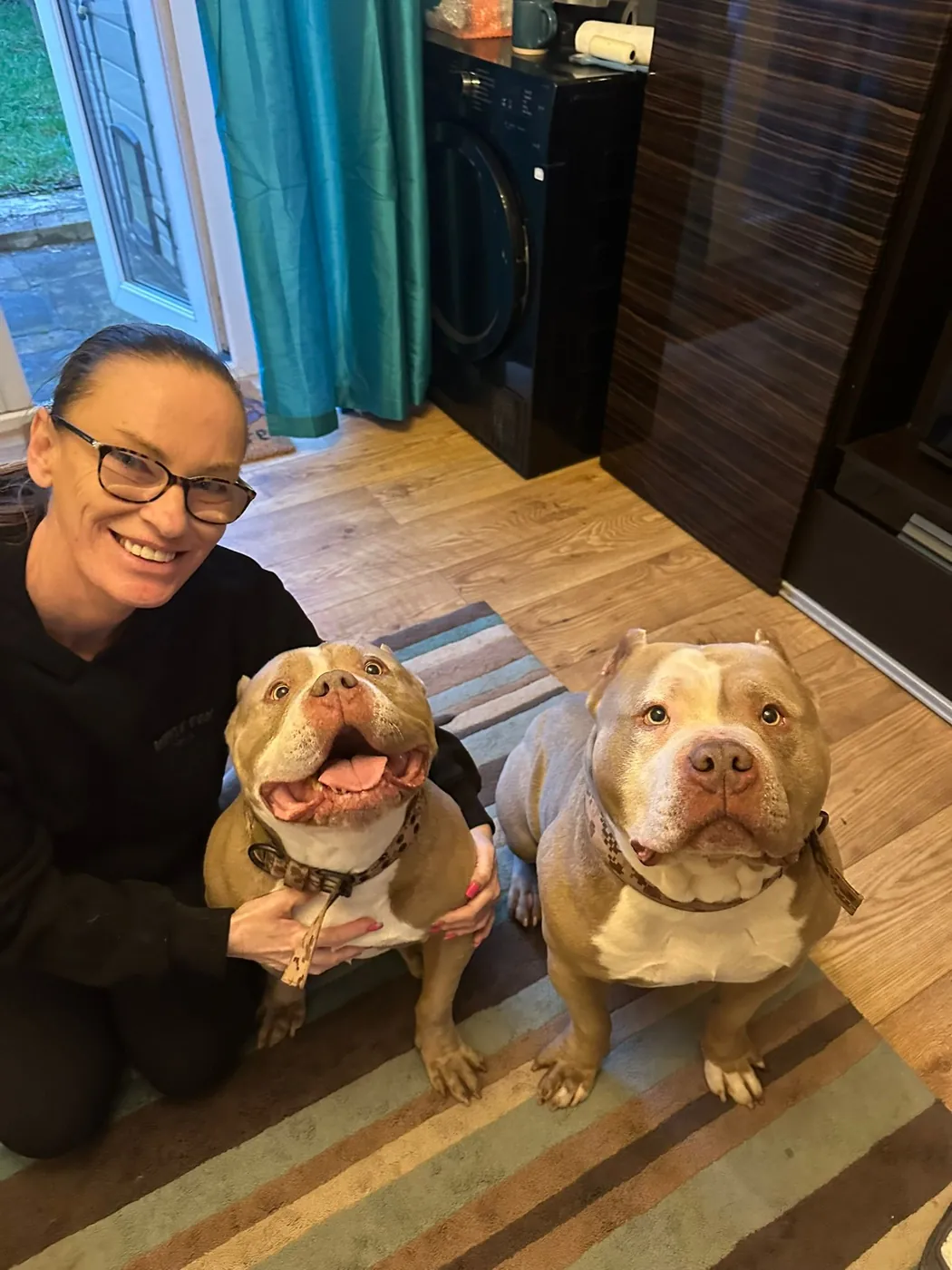 A woman sitting indoors with two rescue dogs